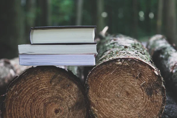 Una pila di libri sdraiati sui tronchi, salvare alberi - leggere ebooks co — Foto Stock