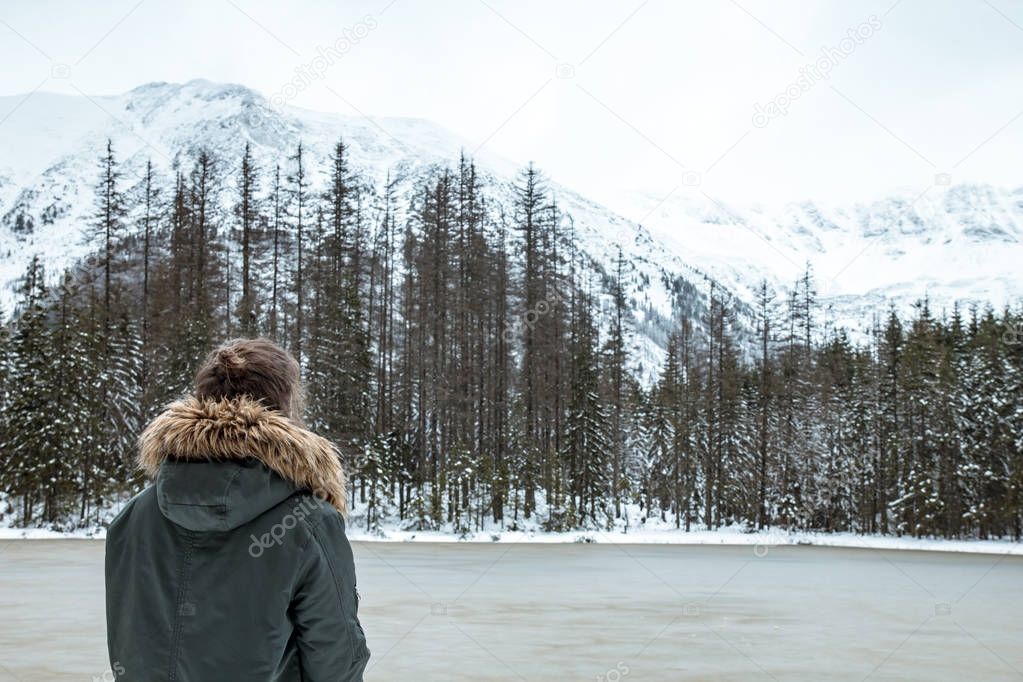 Girl looks at the mountain landscape and frozen lake