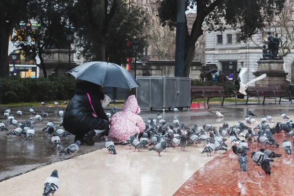 Anne ve kızı güvercinler ra sırasında meydanda besleniyor