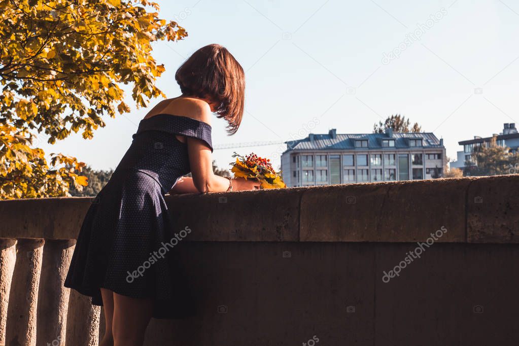 Young girl in blue dress with a bouquet of yellow autumn leaves 