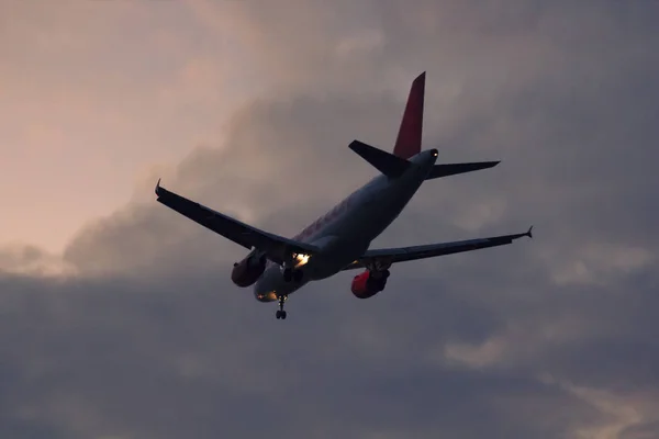 Avião de passageiros decola contra o crepúsculo e vermelho e azul — Fotografia de Stock