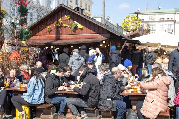 KRAKOW, POLONIA, 2 de abril de 2018, Mucha gente se sienta en una gran t de madera — Foto de Stock