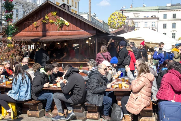 KRAKOW, POLONIA, 2 de abril de 2018, Mucha gente se sienta en una gran t de madera — Foto de Stock