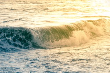 Mavi ve sarı dönen deniz dalgası gün batımında kıyıyı sular altında bıraktı