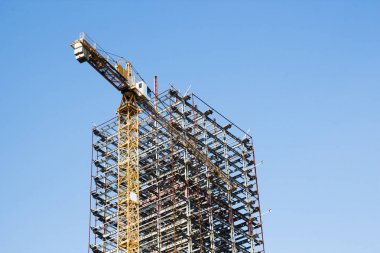 Büyük sarı inşaat vinç ve bitmemiş bir iskelet 