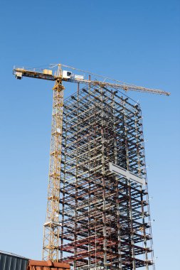 Büyük sarı inşaat vinç ve bitmemiş bir iskelet 