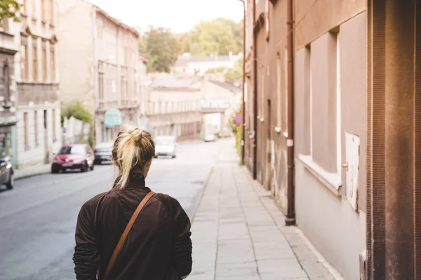 Chica rubia joven caminando por una calle desierta del casco antiguo — Foto de Stock