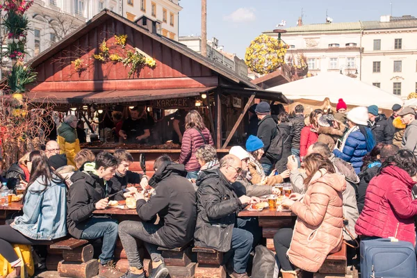 KRAKOW, POLONIA, 2 de abril de 2018, Mucha gente se sienta en una gran t de madera — Foto de Stock