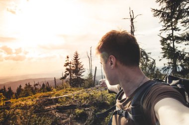 Young man tourist taking a selfie and pointing at a fallen tree  clipart