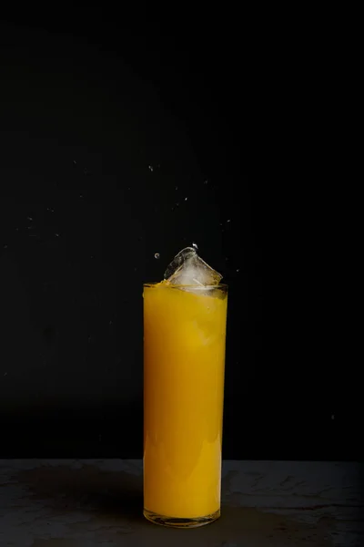 Glass of orange juice with splash, isolated on black background — Stock Photo, Image