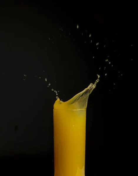 Ποτήρι χυμό πορτοκαλιού με παφλασμό, απομονώνονται σε μαύρο φόντο — Φωτογραφία Αρχείου