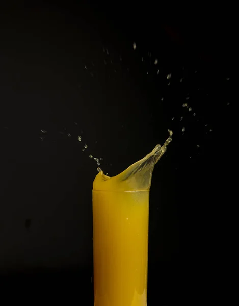 Glass of orange juice with splash, isolated on black background — Stock Photo, Image