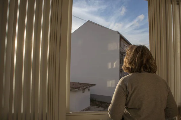 Женщина средних лет у окна с прекрасным светом заката — стоковое фото