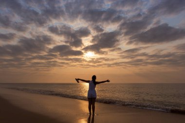 Kollarını açarak, sunset ve dramati genç kızla silüeti