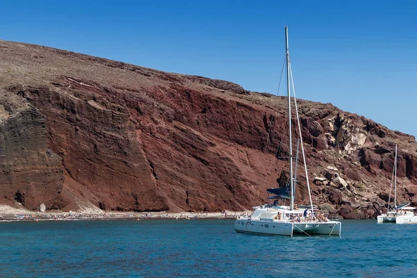 Katamaran ile denizin Santorini görünümünde kırmızı plaj