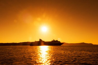 Deniz, gün batımı ile cruise gemi silueti.