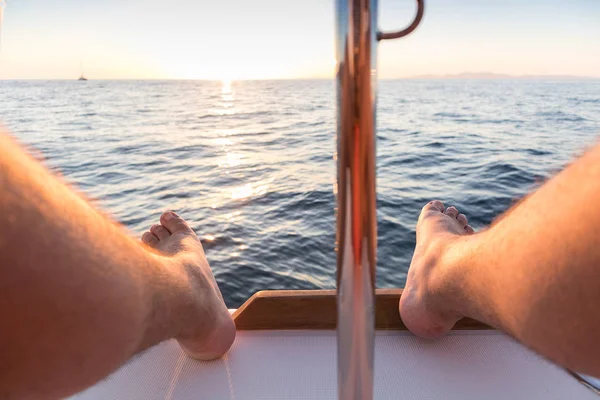 Gün batımı ve deniz manzaralı adamın ayakları.