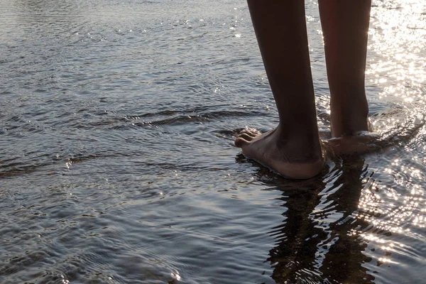 African dziewczyna nogi chodzić nad wodą z lig zachód słońca — Zdjęcie stockowe