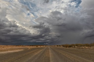 Fırtınalı gökyüzü, hedefe doğru Namibya Çölü olan çakıl yol. Sossuvlei.
