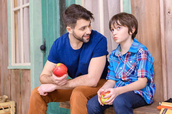 Отец и сын едят яблоки
