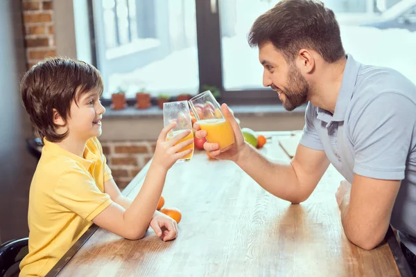 Vader en zoon drinken sap. — Stockfoto