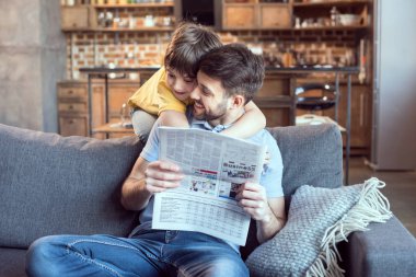 Father and son reading newspaper clipart