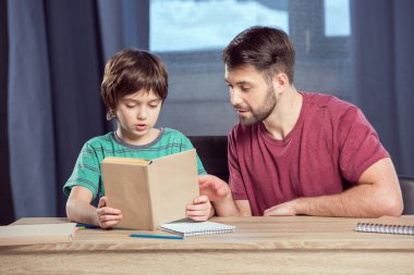 Baba oğluna ödevlerinde yardım ediyor. 