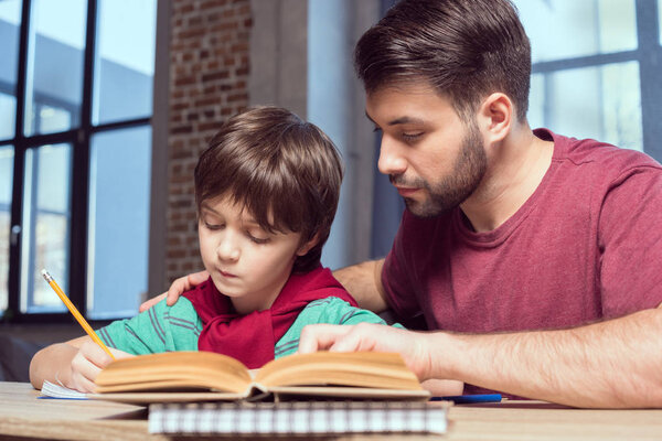 father helping son doing homework  