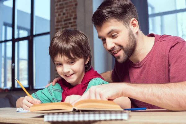 Far hjälper sonen med läxorna. — Stockfoto