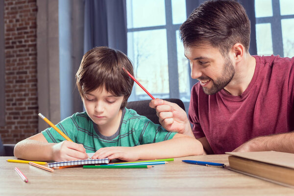 father helping son doing homework 