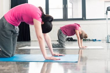 Anne ve kızı yoga yapıyor.