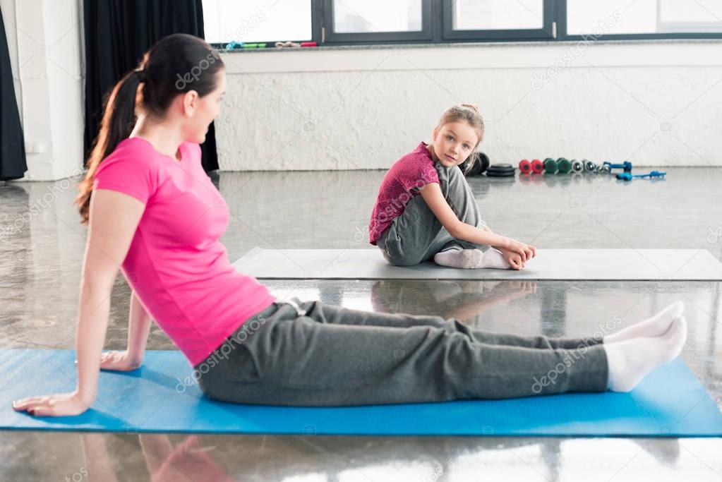 mother and daughter sitting on yoga mats 