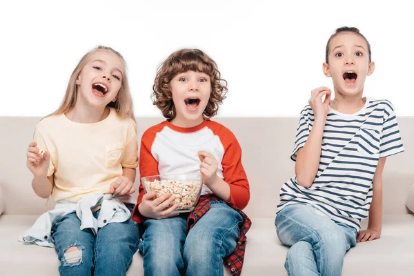 Lindos niños en el sofá con palomitas de maíz — Foto de Stock