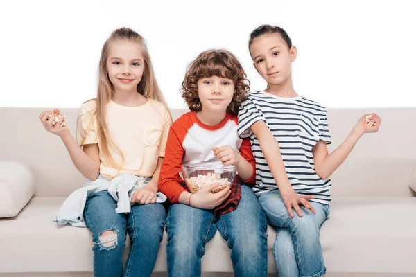 Lindos niños en el sofá con palomitas de maíz — Foto de Stock