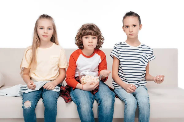 Lindos niños en el sofá con palomitas de maíz — Foto de Stock