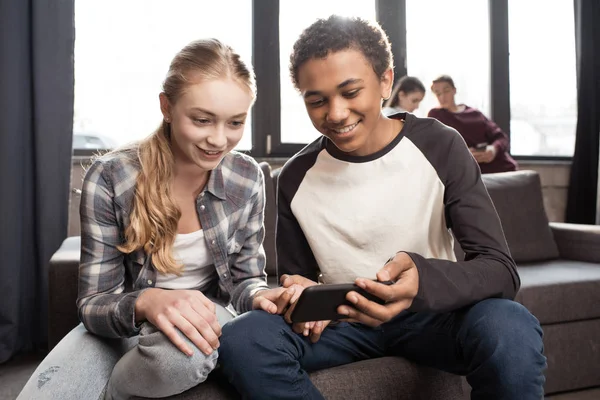 Teenage couple using smartphone — Stock Photo, Image