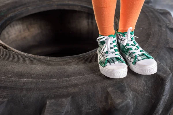 Niño en ropa deportiva de pie sobre el neumático — Foto de Stock