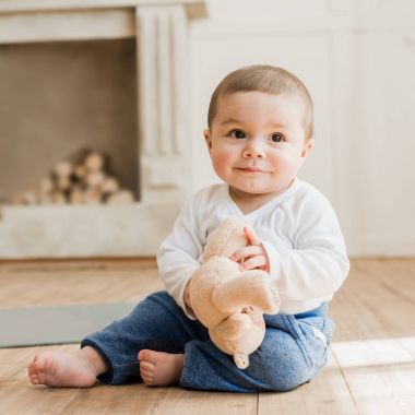 Oyuncak ayı ile oturan bebek boy gülümseyerek 