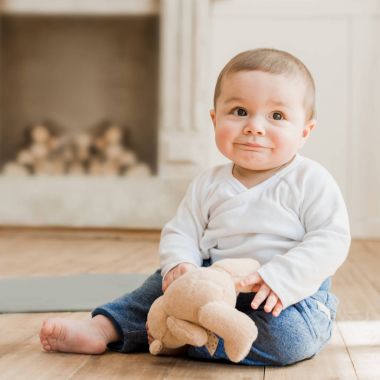 Oyuncak ayı ile oturan bebek boy gülümseyerek 