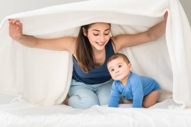 Mother with her son playing under blanket  clipart