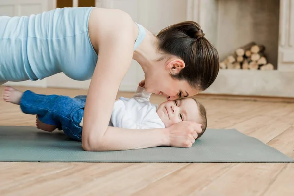 Madre haciendo ejercicio de tablón con su hijo — Foto de Stock