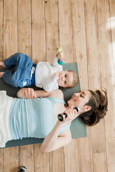 ダンベルと遊ぶ母と赤ちゃんの男の子 — ストック写真