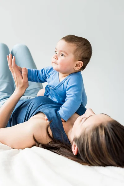 Jonge moeder met kind liggend op bed — Stockfoto