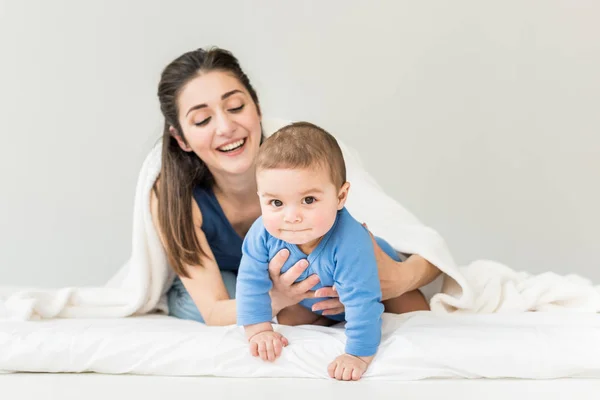 Mãe com seu filho brincando sob cobertor — Fotografia de Stock