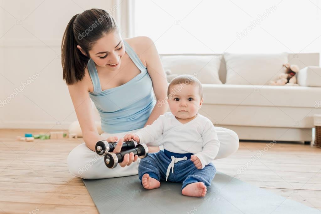 Woman with baby child using dumbbells 