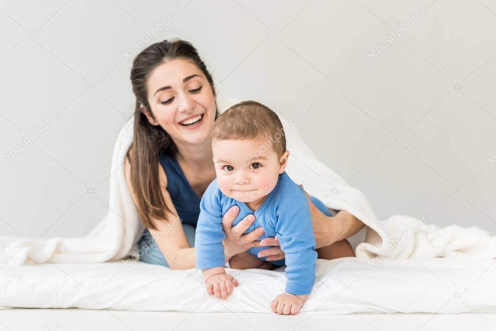 Mother with her son playing under blanket 