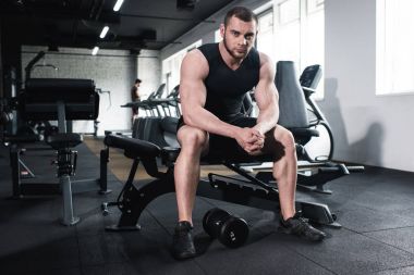 Kameraya bakarak spor salonunda oturan sporcu