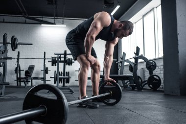 exhausted bodybuilder holding barbell at gym clipart