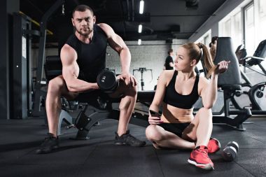 man training while woman holding smartphone clipart