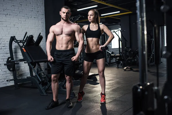 Sportliches Paar posiert im Fitnessstudio — Stockfoto